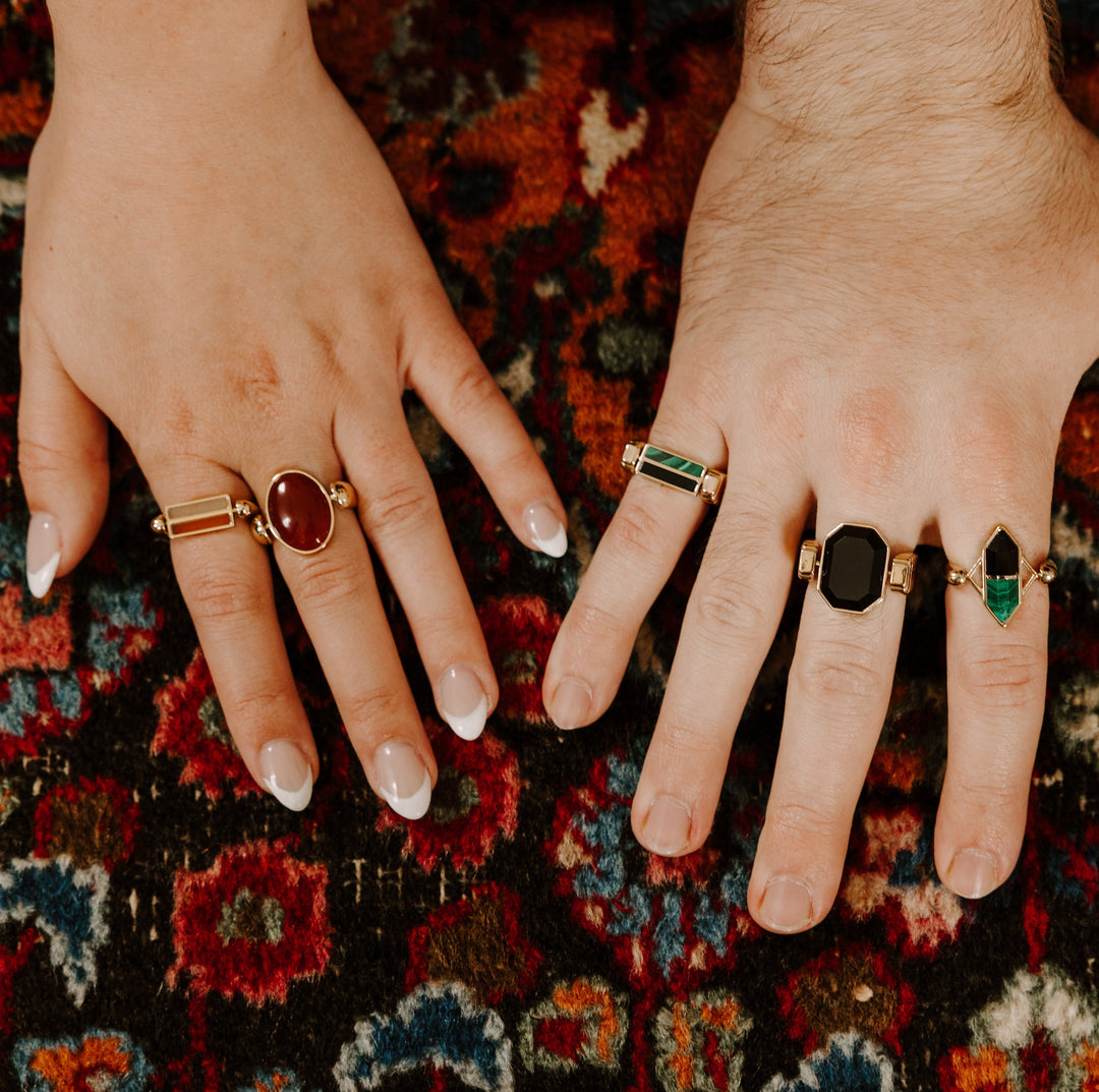Two people putting their hands on decorative carpet wearing crystal fidget rings