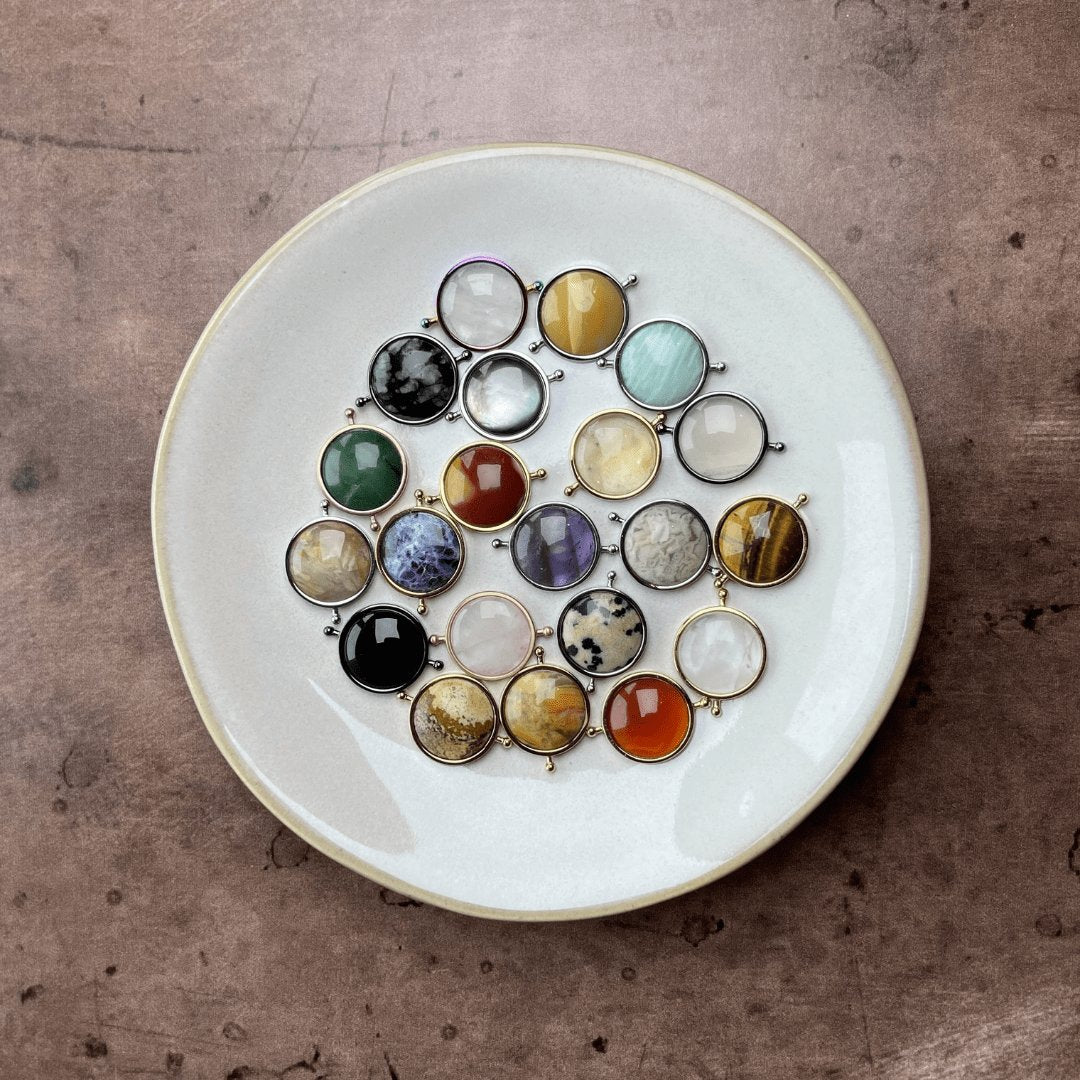 colorful crystal collection spinners in two cream dishes on stone background