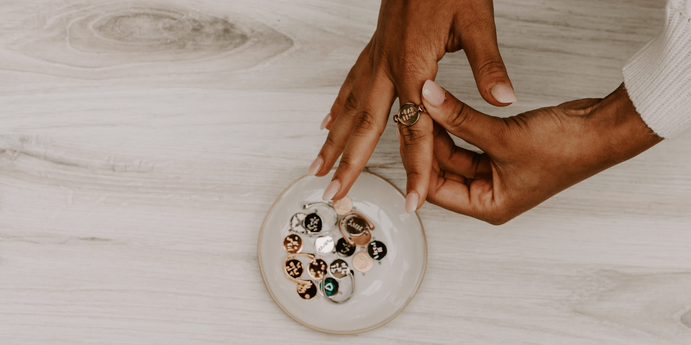 close up of hands trying on a gold CONQUERing, with a dish of other spinners nearby