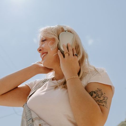 Person standing in front of the sky listening to music, wearing fidget rings