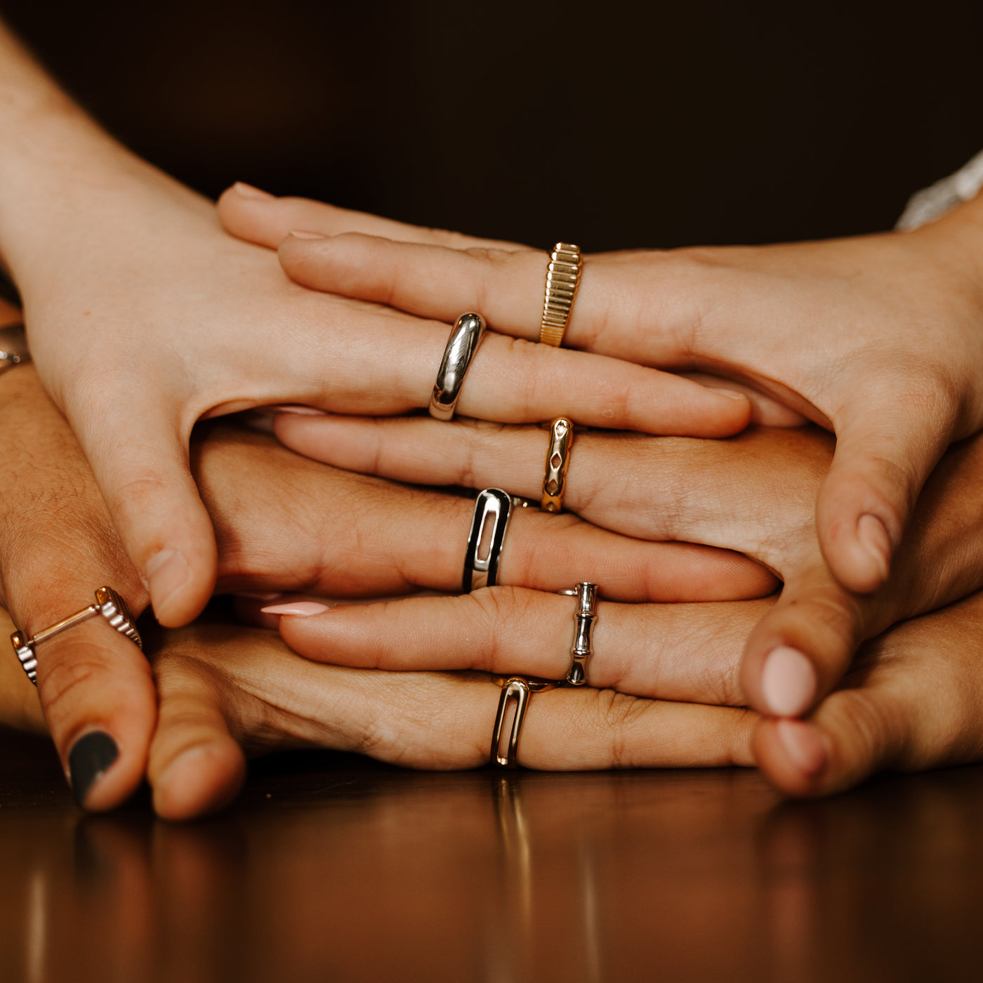 Multiple people stacking their hands wearing fidget rings