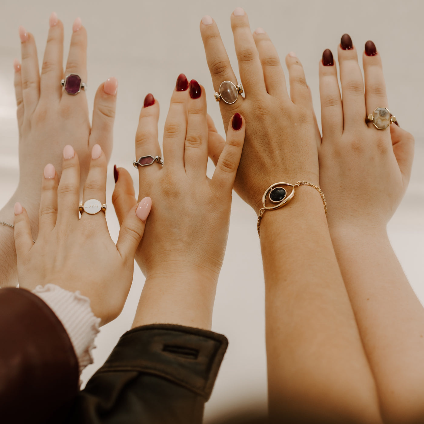 Five people holding up their hands wearing silver and gold fidget rings and bracelets