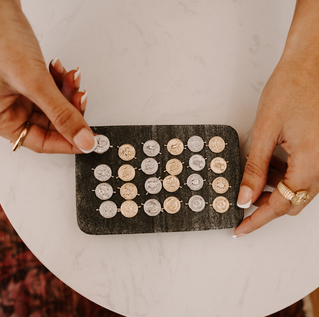 Person organizing luxe zodiac elements for interchangeable jewelry
