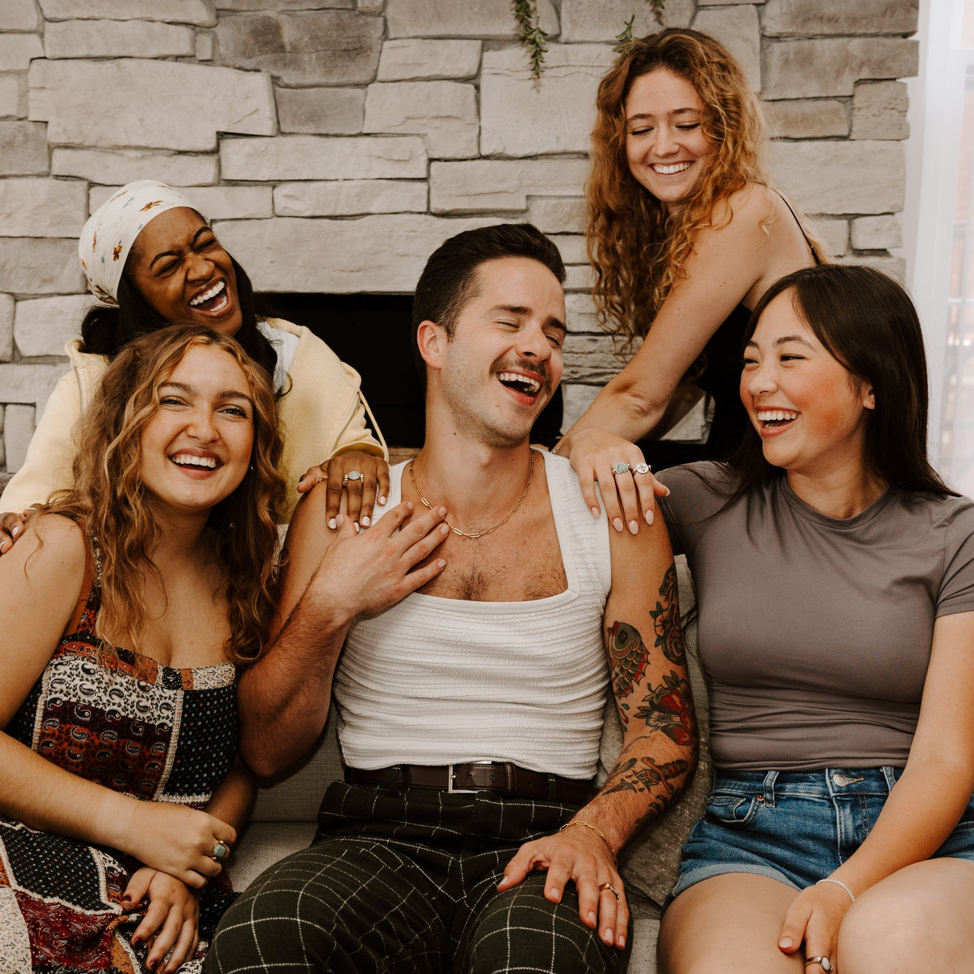 Five people sitting and laughing together all wearing fidget jewelry for anxiety