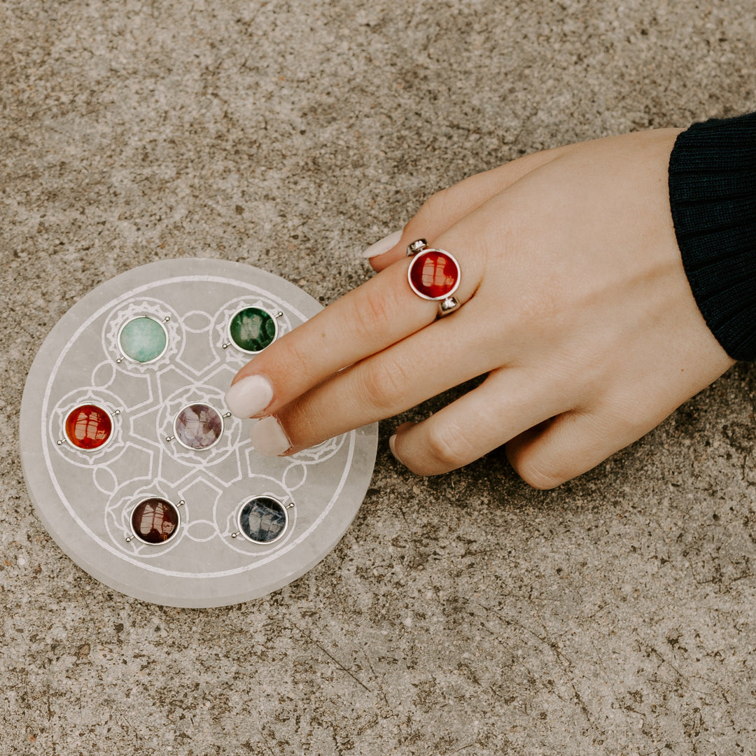 Photograph of person wearing Carnelian fidget ring and pointing at selenite plate with other crystals