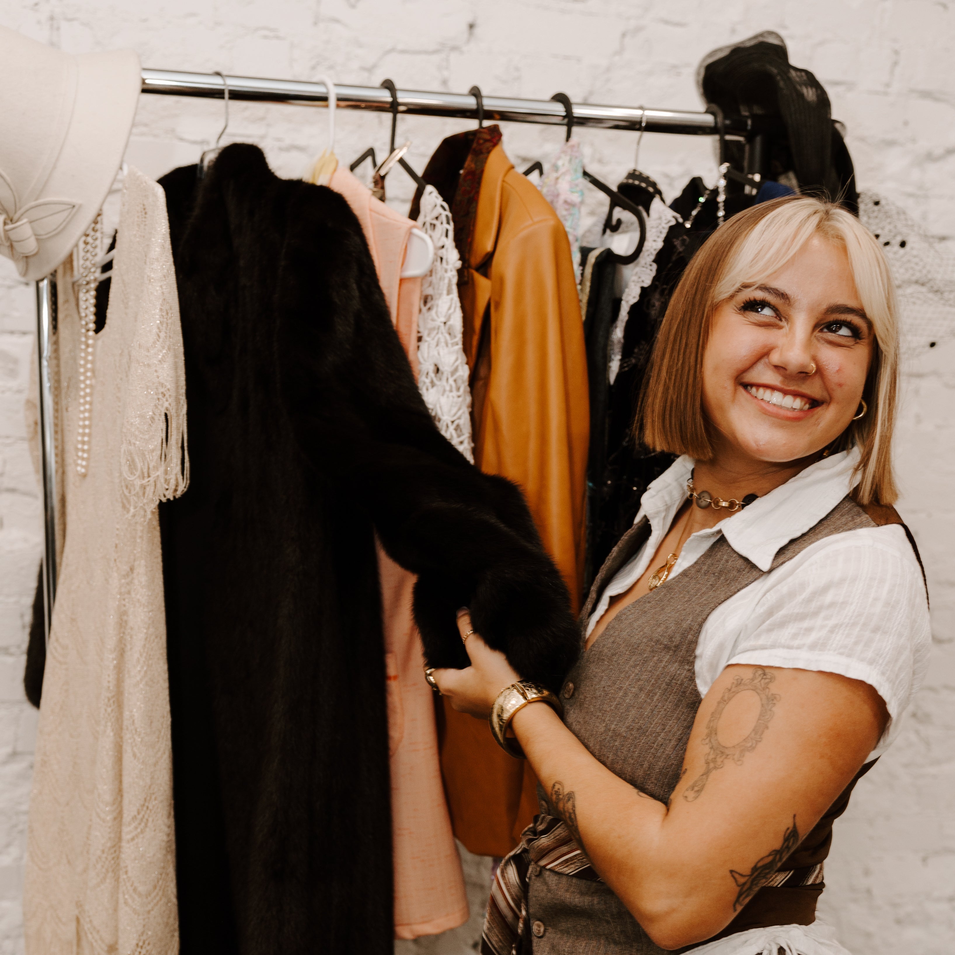Person posing in front of a clothing rack preparing for a clothing swap