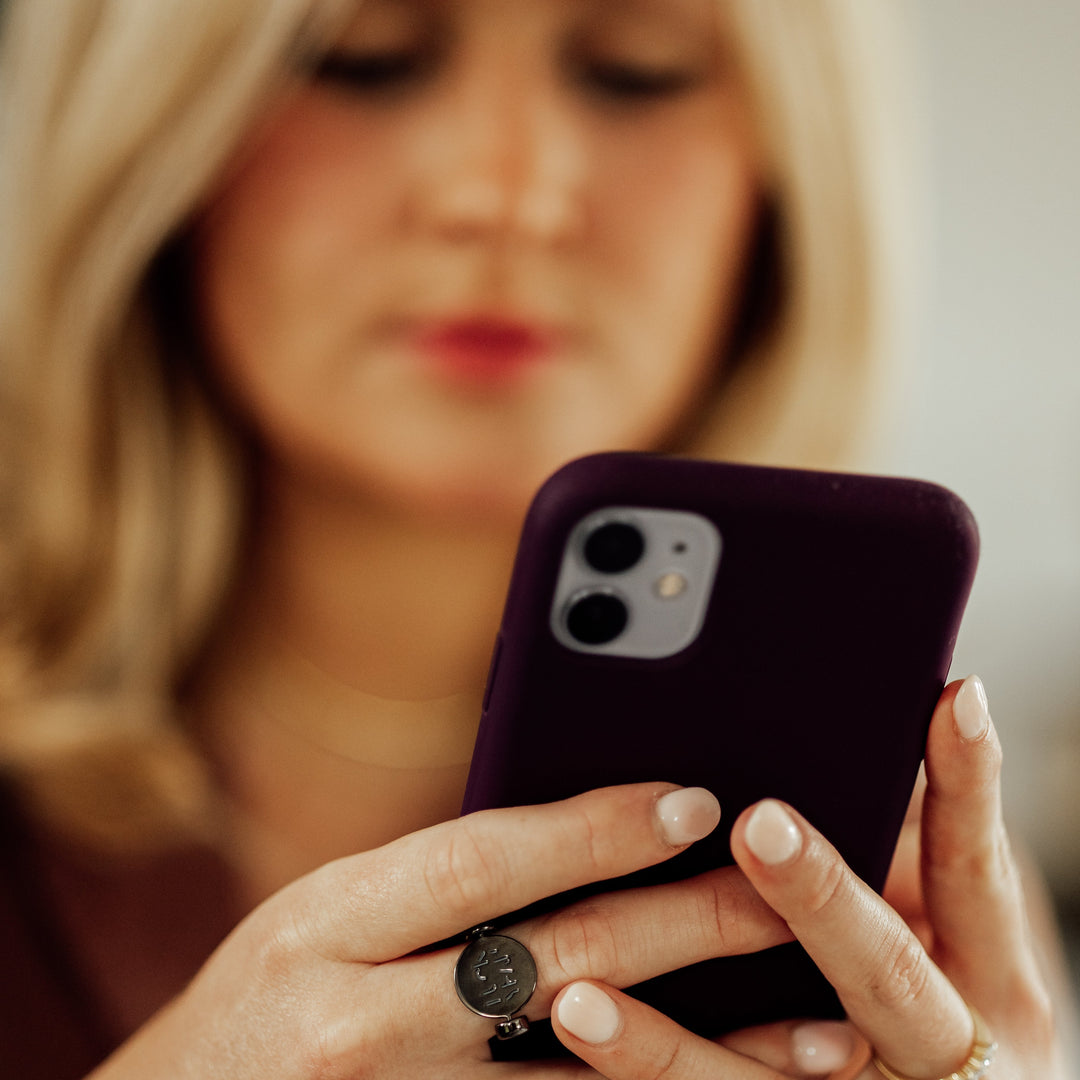 Photo of person staring at an iPhone wearing silver fidget ring