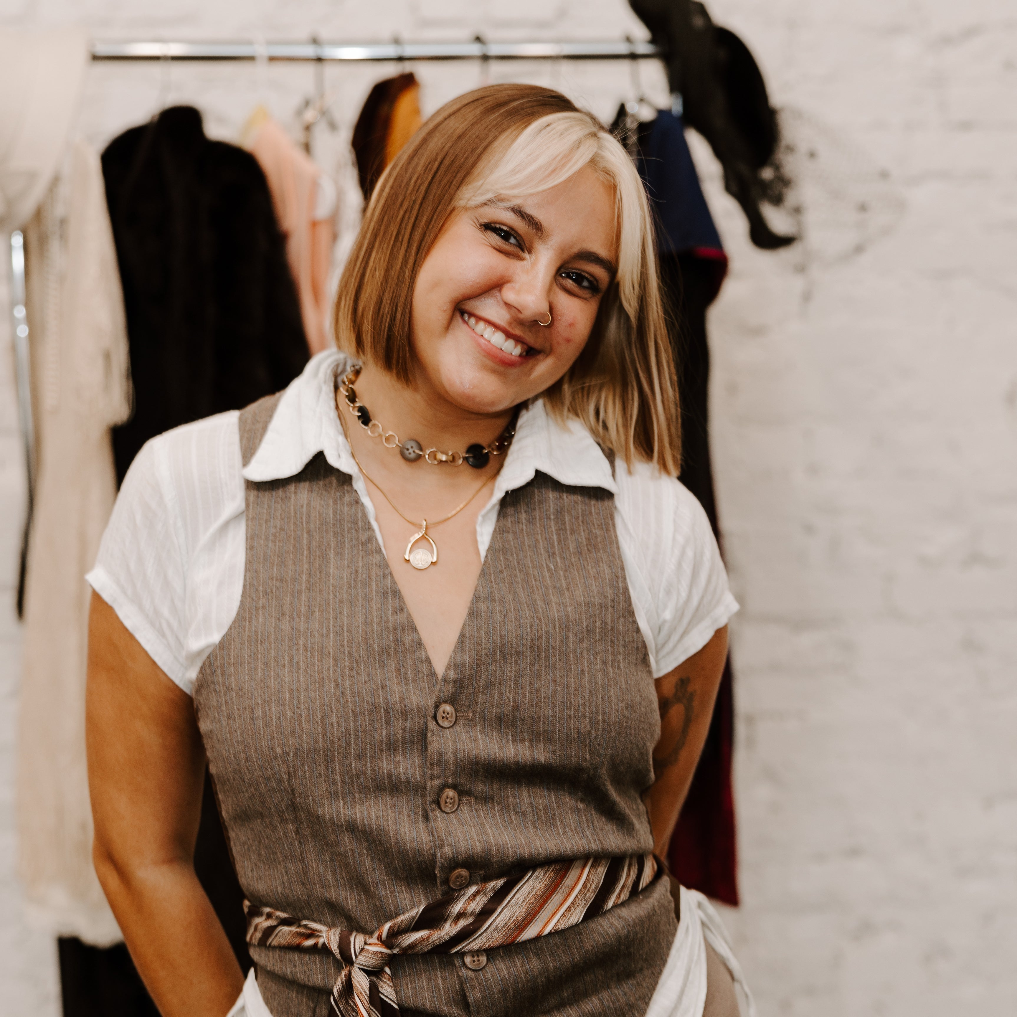 Stylist for Decades Styling Series posing in front of rack of clothes