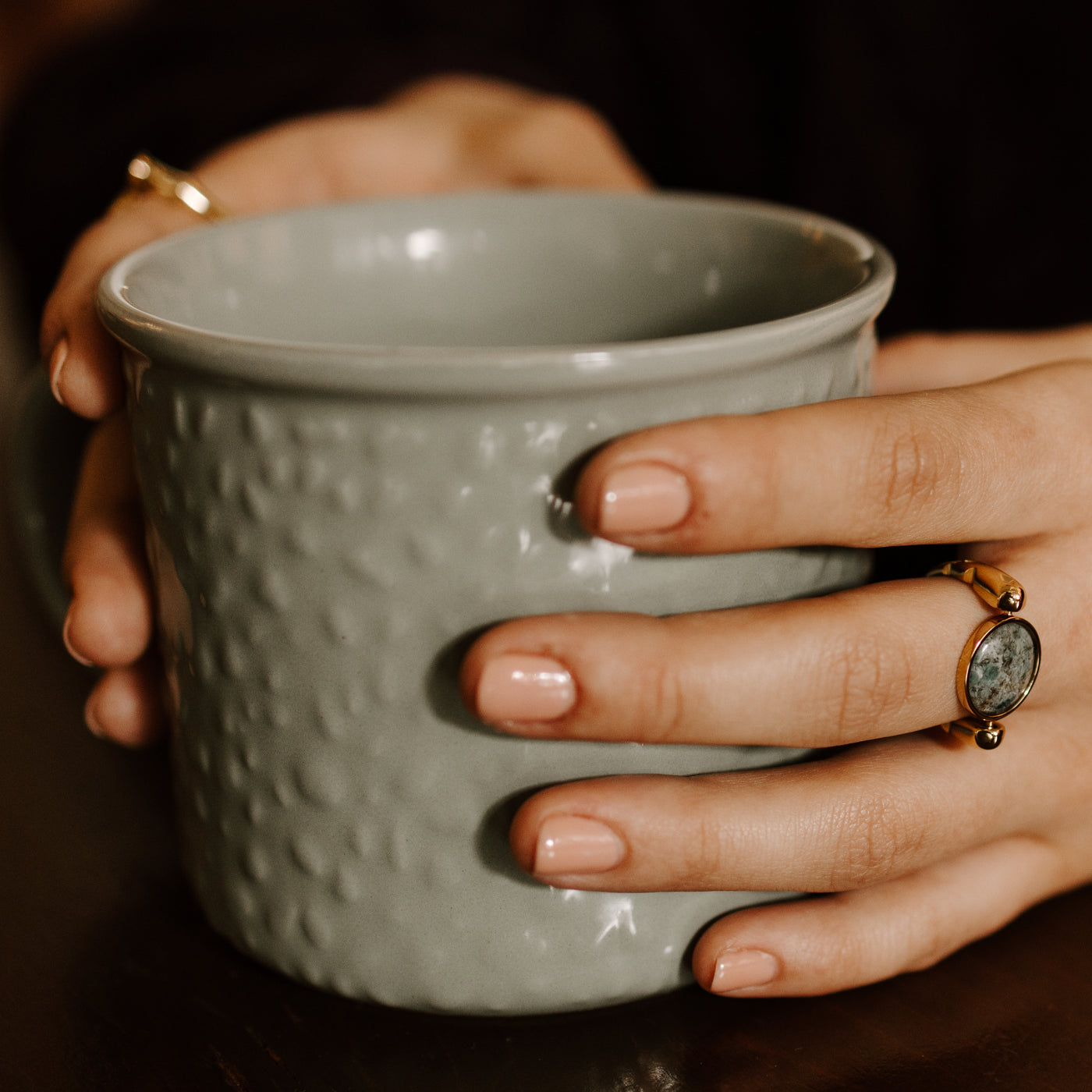 Person holding a coffee mug wearing a Fisheye Agate Fidget Ring