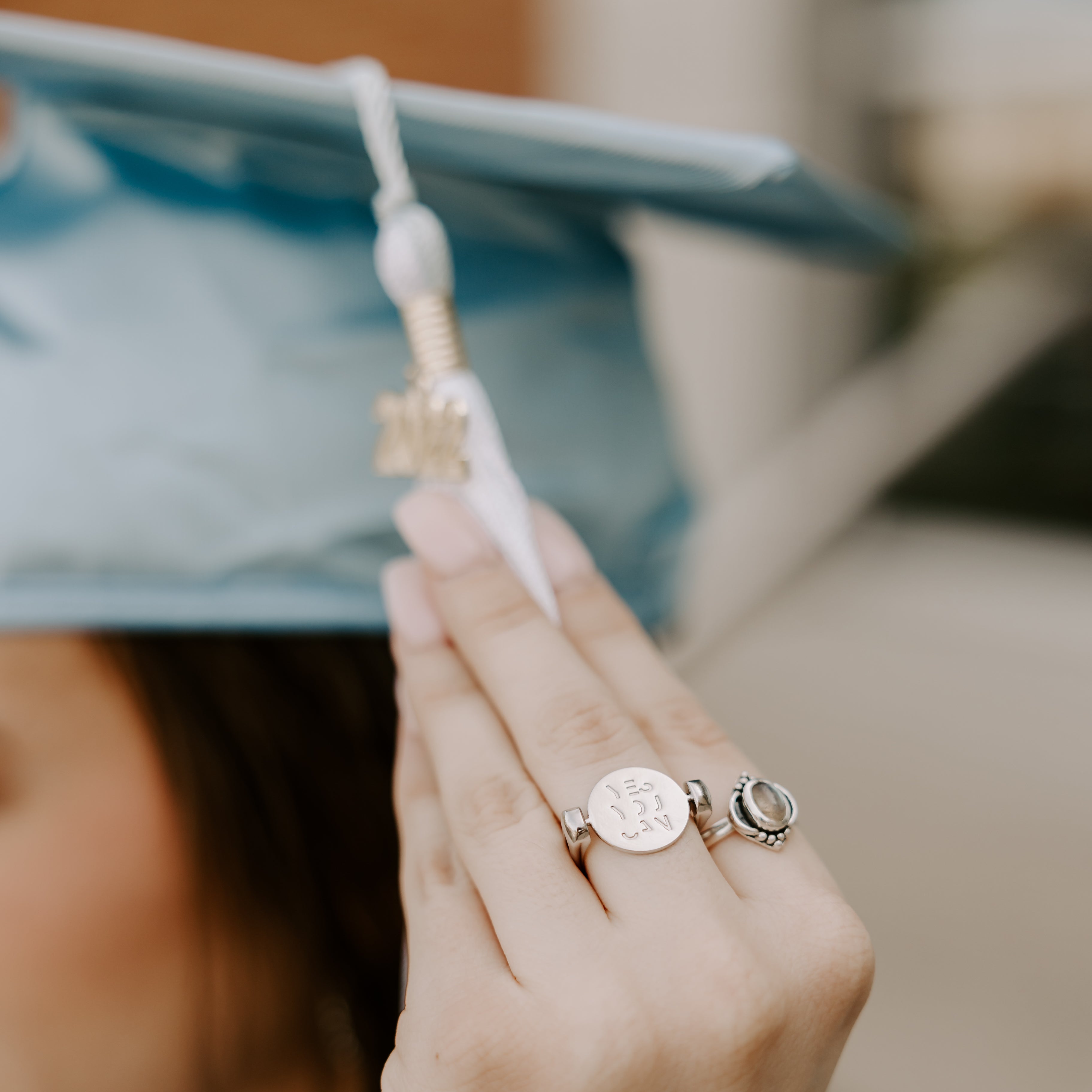 Person holding a graduation tassel wearing silver fidget ring