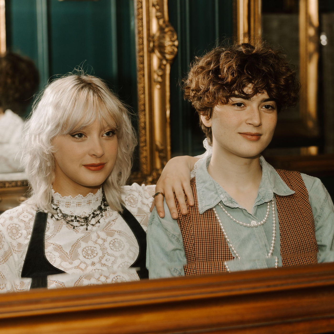 Two people looking in a mirror, wearing CONQUERing jewelry