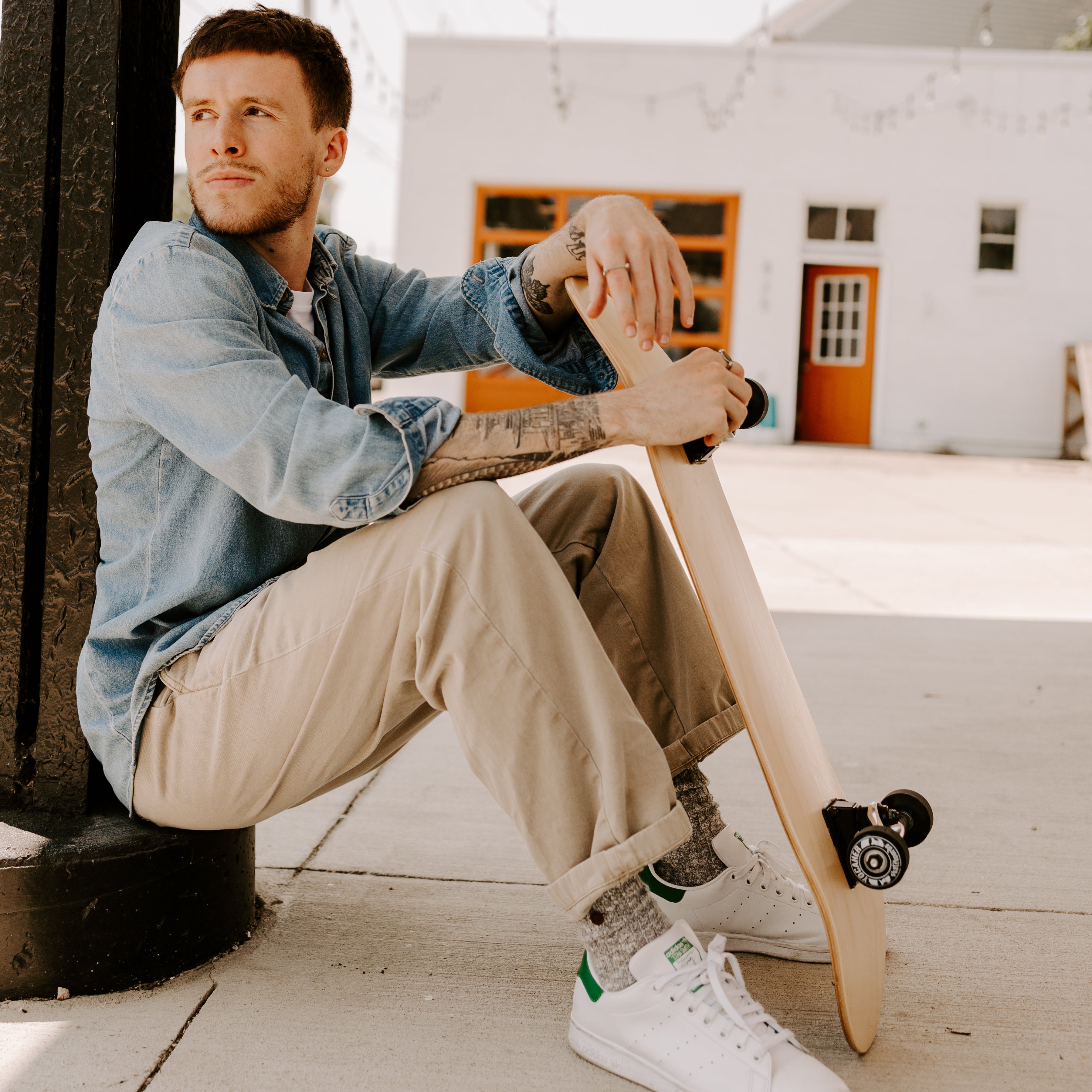 Person sitting outside, holding a skateboard, and waring fidget jewelry