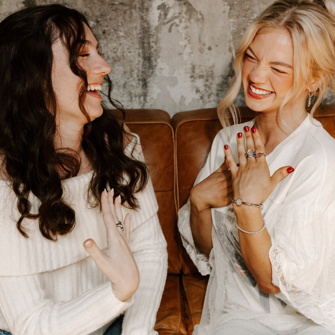 Two people sitting on a couch modeling fidget jewelry