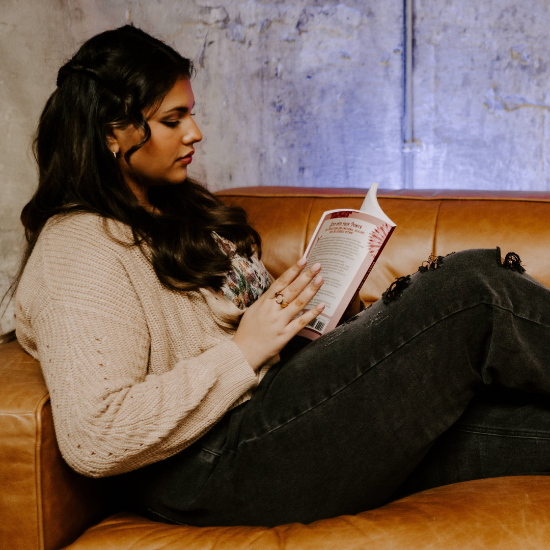Photograph of person reading a book sitting on a couch and wearing fidget jewelry