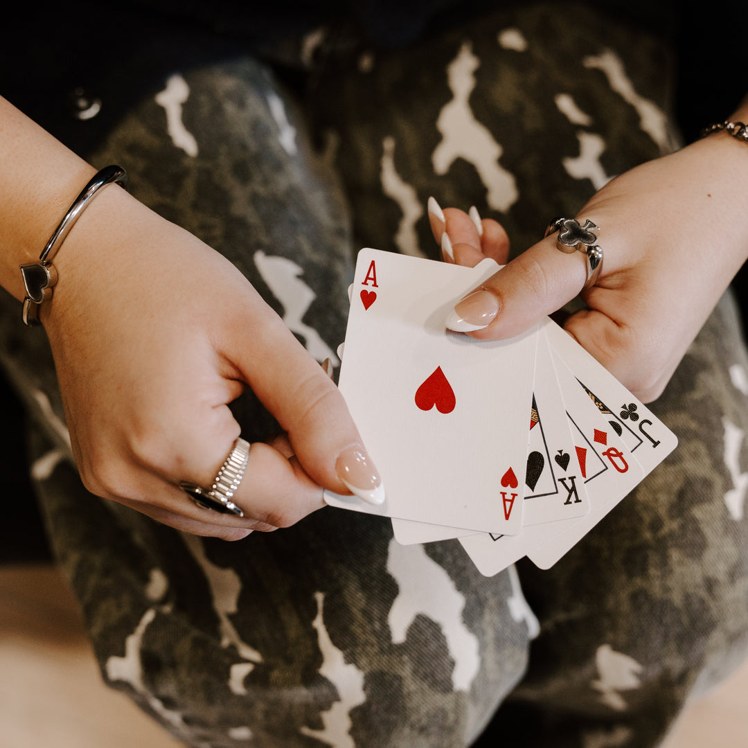 Photograph of person holding playing cards wearing card-inspired fidget jewelry