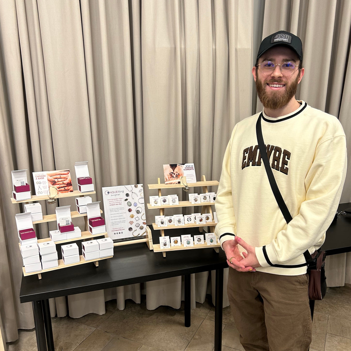 CONQUERing co-creator in front of display of CONQUERing jewelry