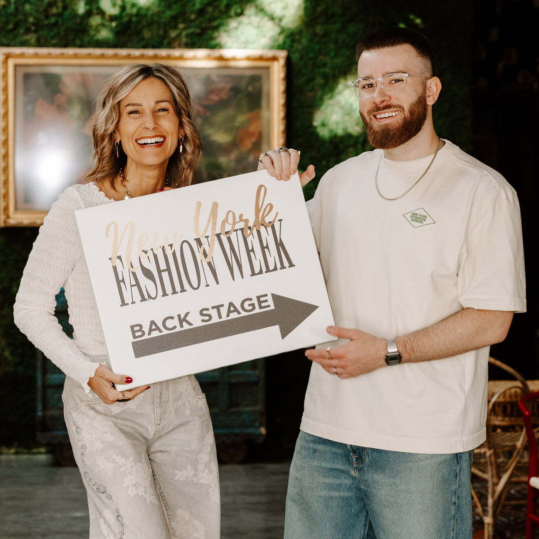 CONQUERing co-founders holding a sign that says New York Fashion Week Backstage