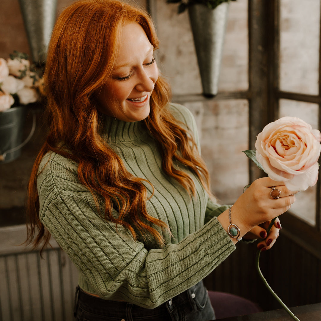 Person putting a rose in a flower arrangement wearing fidget jewelry