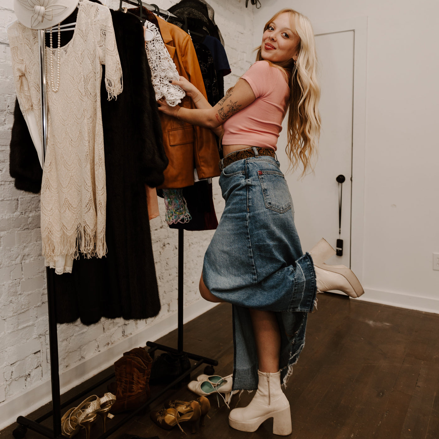 Stylist posing in front of rack of clothes