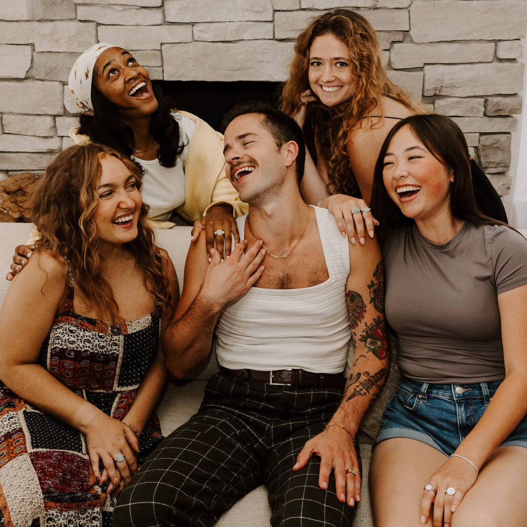 Group of people sitting together and laughing, wearing fidget jewelry