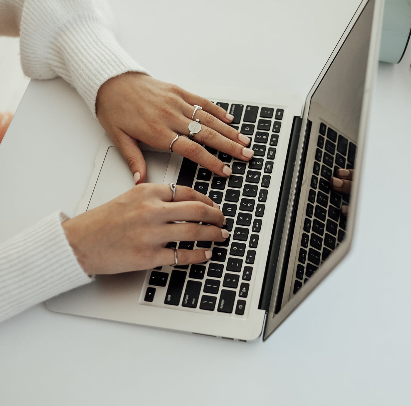 Person typing on a laptop wearing silver fidget jewelry