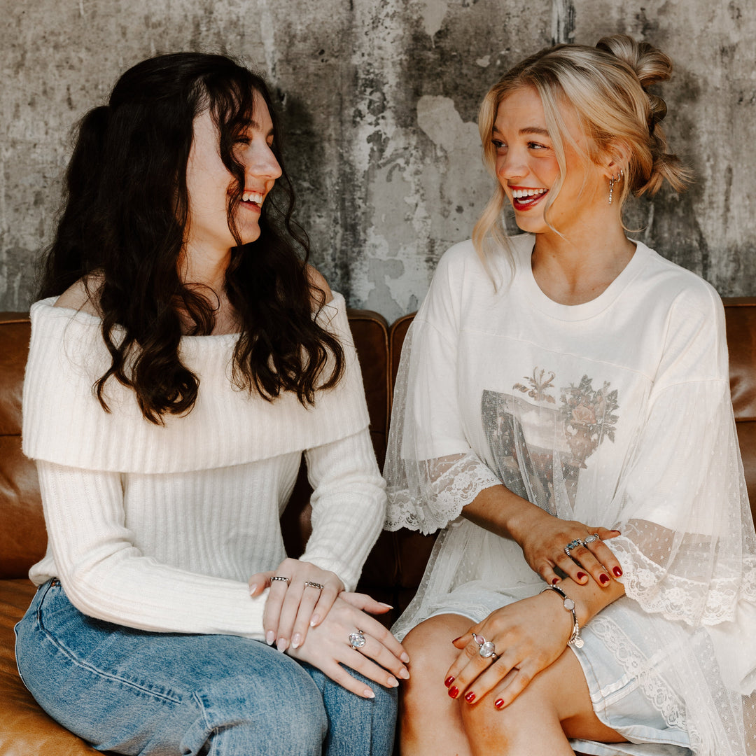 Two people sitting on a couch talking to each other wearing fidget jewelry