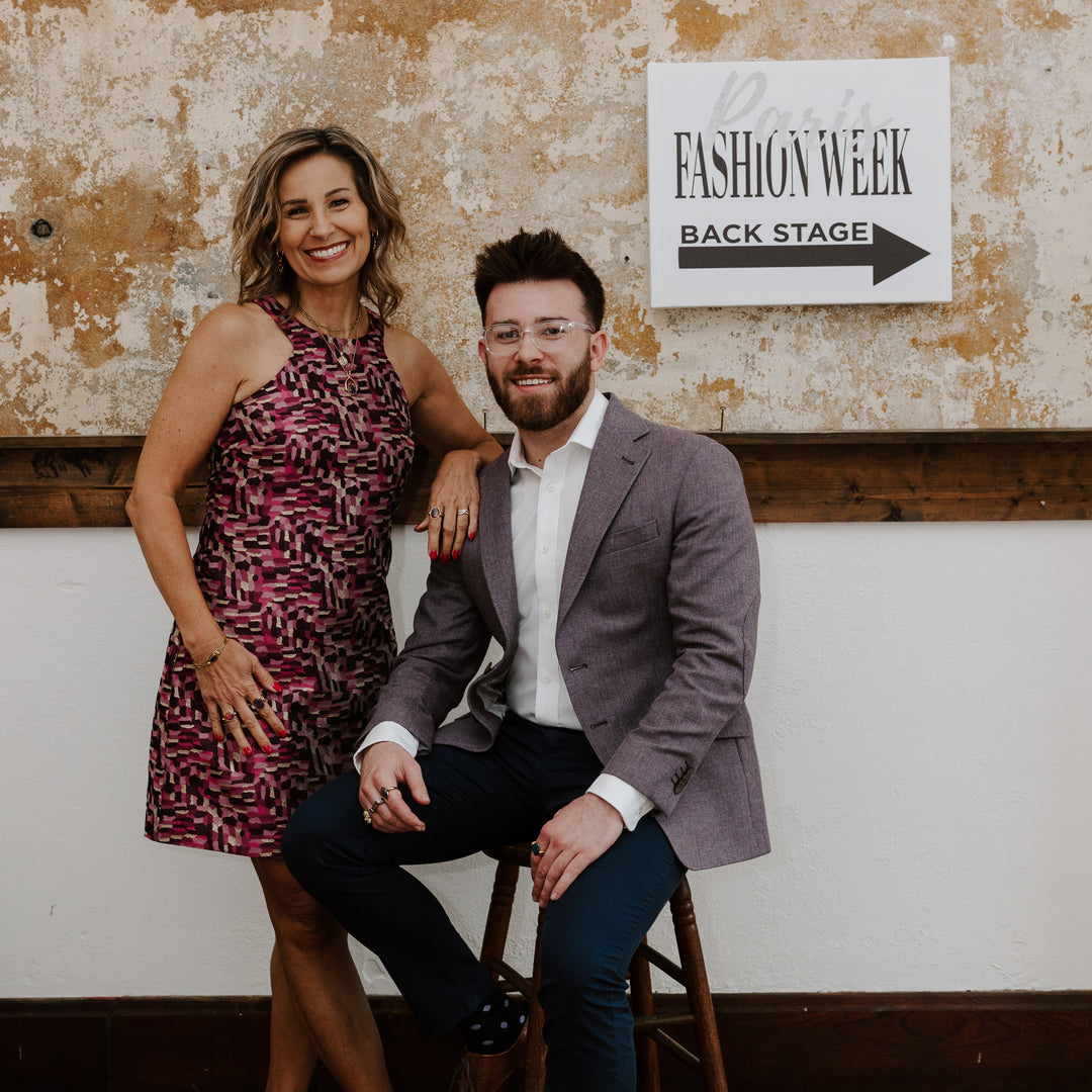 Two people posing in front of a sign that says Paris Fashion Week