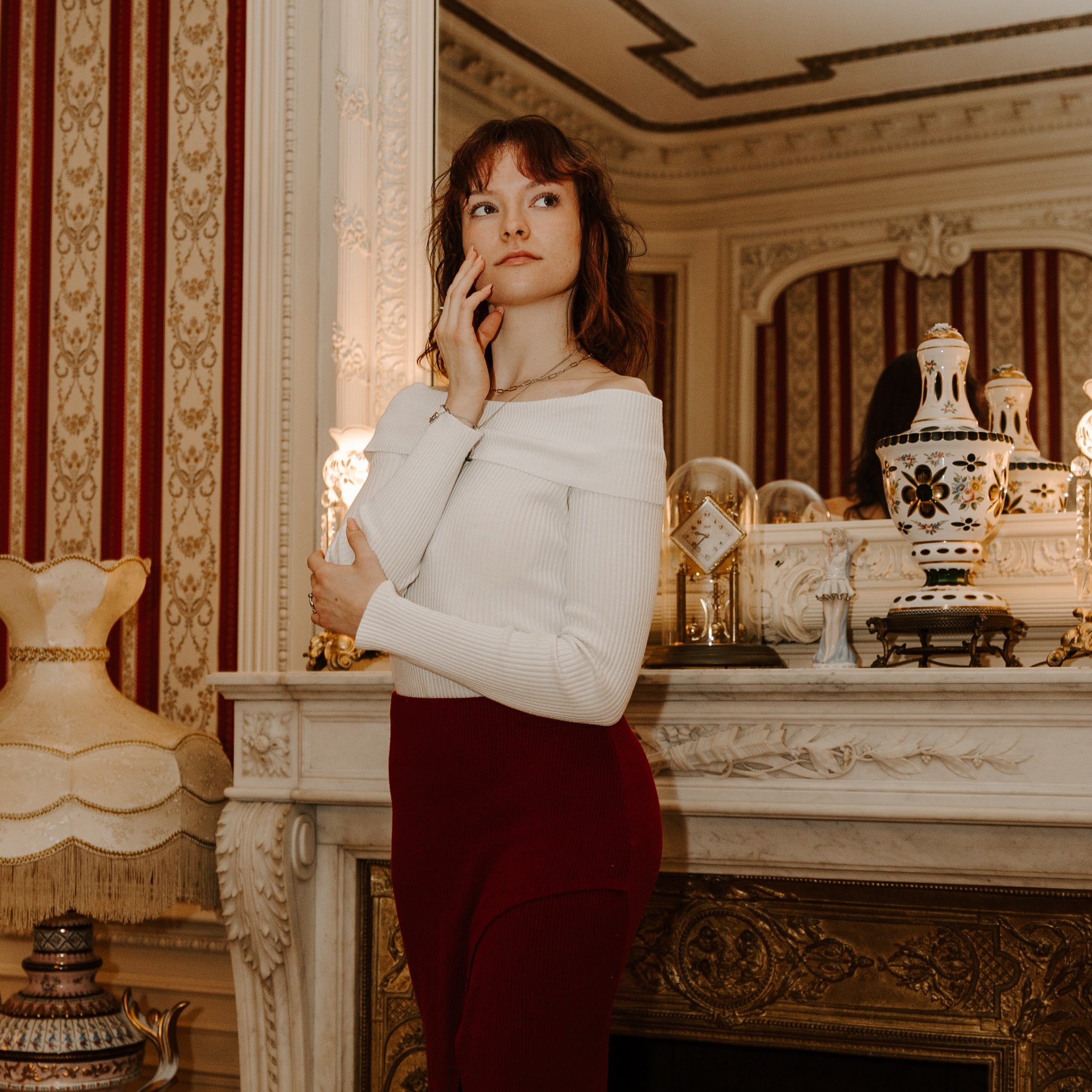 Person posing in front of a regal fire place looking contemplative and wearing fidget jewelry