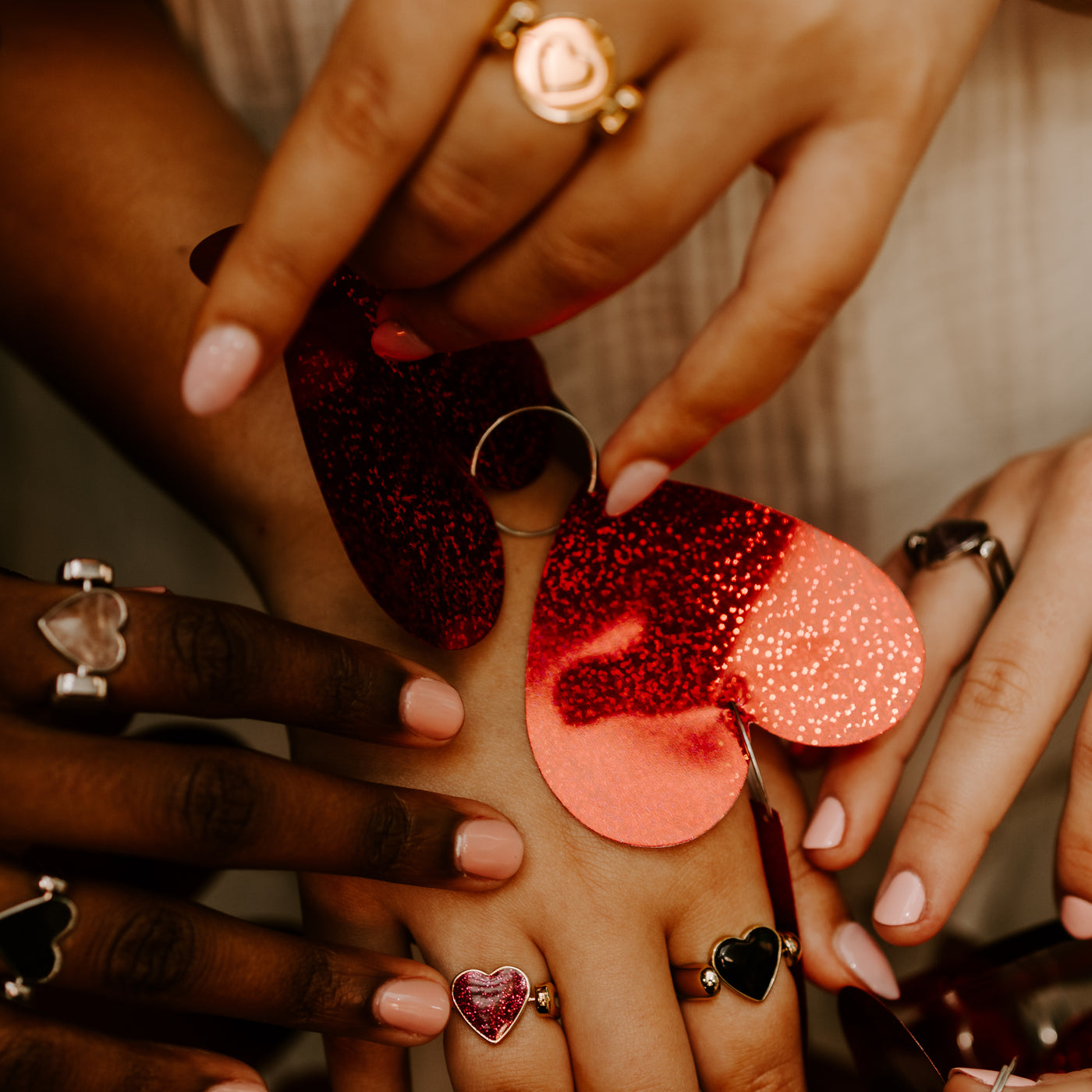 Four people wearing heart-shaped fidget jewelry around a red heart.