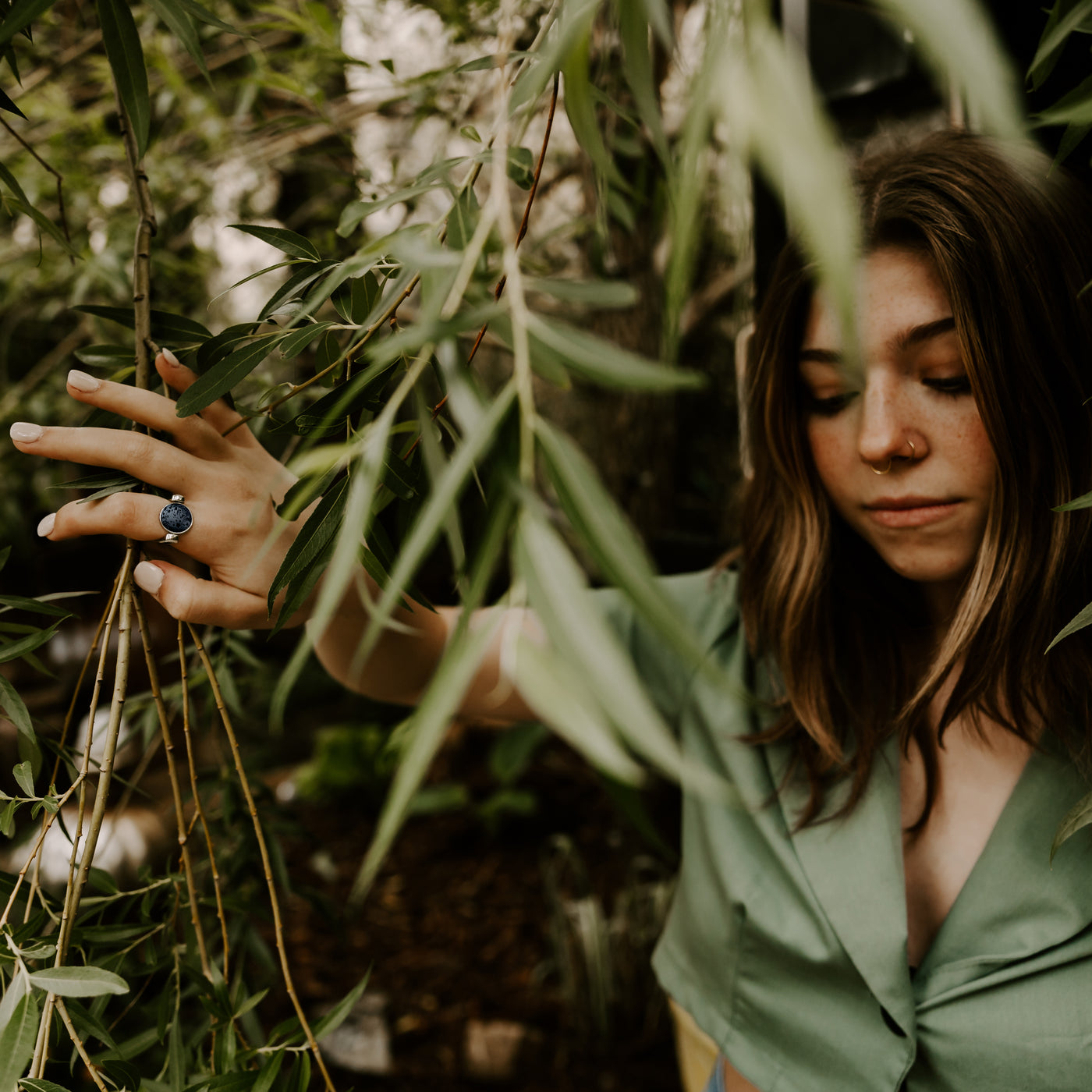 Person standing in trees wearing a silver lava stone fidget ring