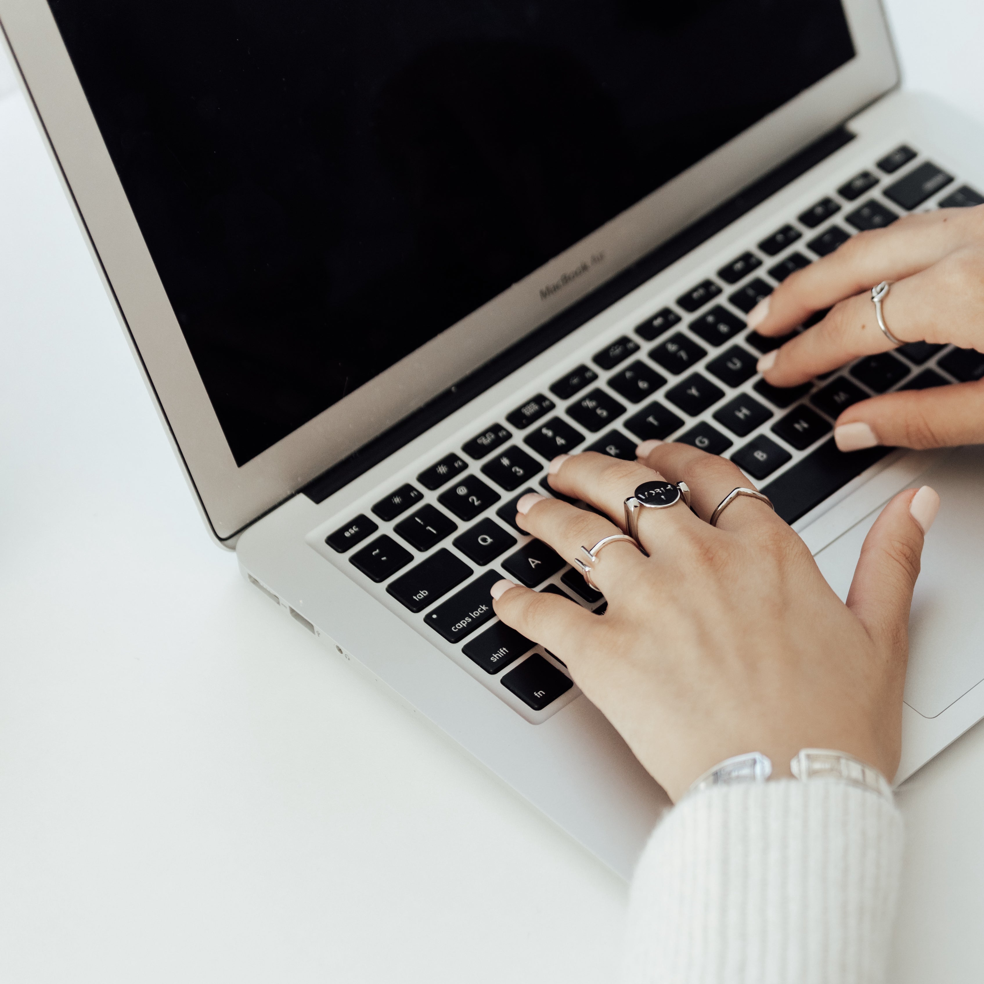 Person typing on a laptop wearing fidget rings