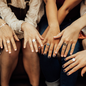 5 female hands held out, all wearing silver conquerings